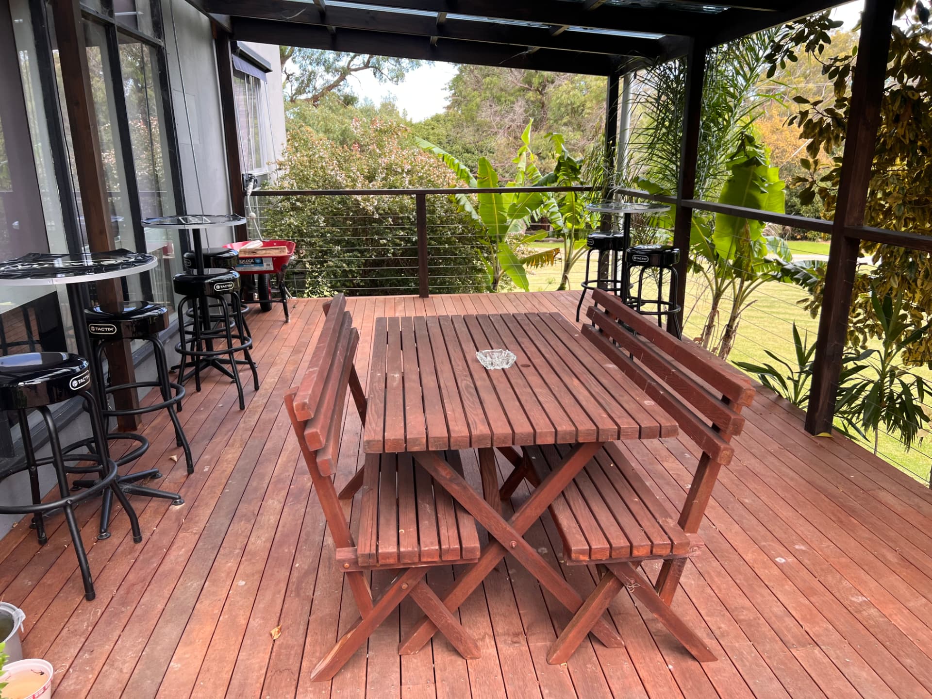 Covered timber deck with long table, benches and bar stools at the 5 bedroom apartment